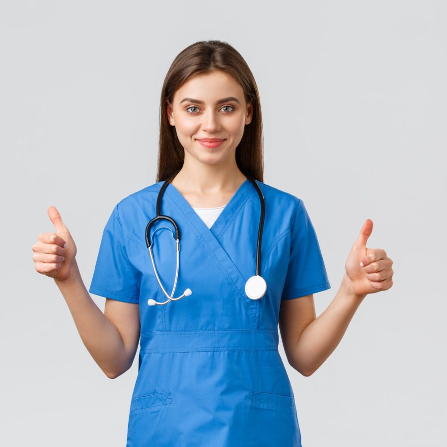 Healthcare workers, prevent virus, insurance and medicine concept. Supportive professional female nurse or doctor in blue scrubs, stethoscope, show thumbs-up in approval, smiling.